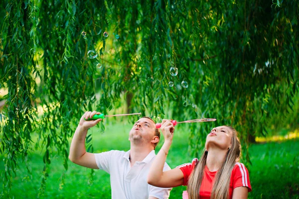 Casal Relaxante no Parque com soprador de bolhas. Hora da Primavera — Fotografia de Stock