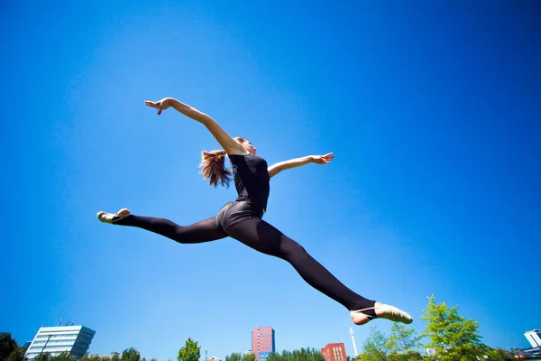 Leende unga gymnasten hoppning i split och svävar ovanför den — Stockfoto