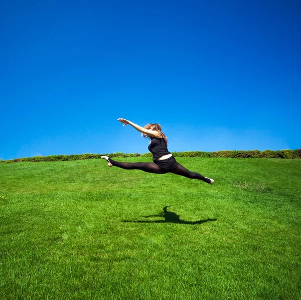 Gülümseyen genç jimnastikçi bölmedeki atlama ve yukarıda yüzen