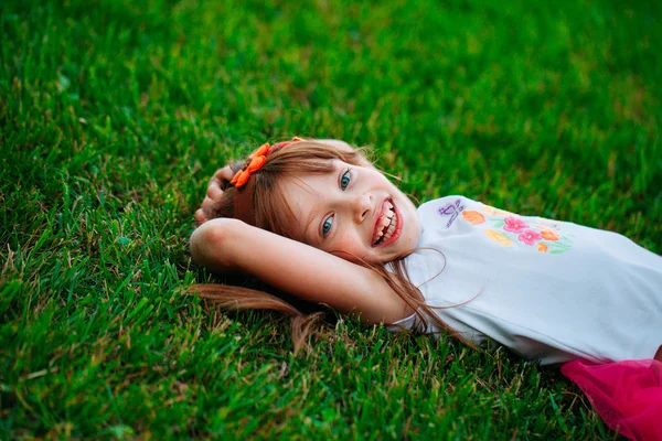 Lilla flickan liggande i gräset — Stockfoto
