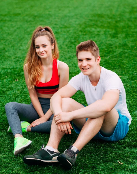 Jeune couple athlétique assis sur l'herbe — Photo