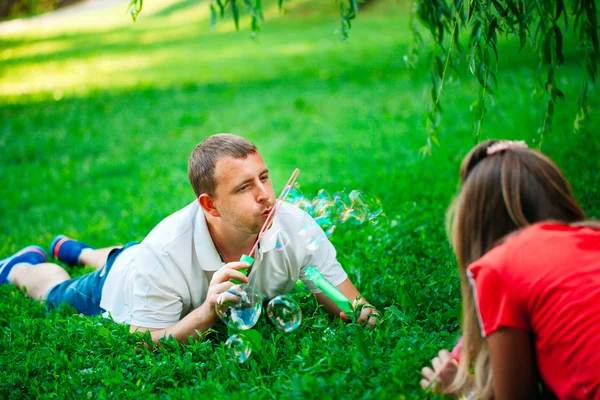 Pareja Relajante en el Parque con soplador de burbujas. Primavera — Foto de Stock