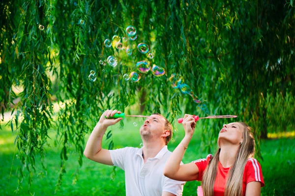 Casal Relaxante no Parque com soprador de bolhas. Hora da Primavera — Fotografia de Stock
