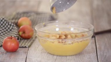 Elmaları hamura katlamak için kauçuk spatula kullanan kadın doğranmış elma ekliyor..