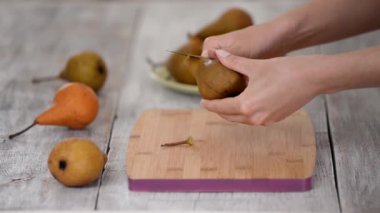 Masanın üzerinde armut soyan kadın..