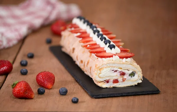 Yaban mersini ve çilekle süslenmiş kremalı pasta.