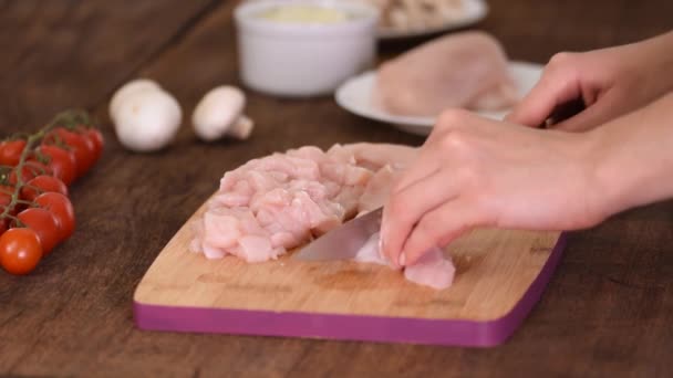Samičí ruce krájení kuřecí filet na dřevěné sekací desce. — Stock video