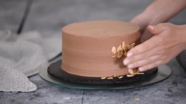 Dişi pasta şefi bir pasta hazırlıyor ve onu badem gevreğiyle süslüyor..