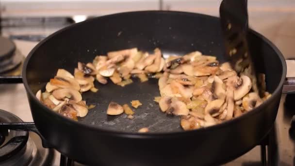 잘게 썬 양파와 잘게 썬 버섯을 프라이팬 위에 섞어 접는다. — 비디오