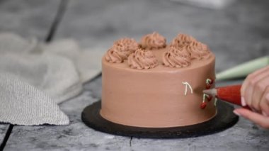 Şef çikolatalı keki kremayla süslüyor..