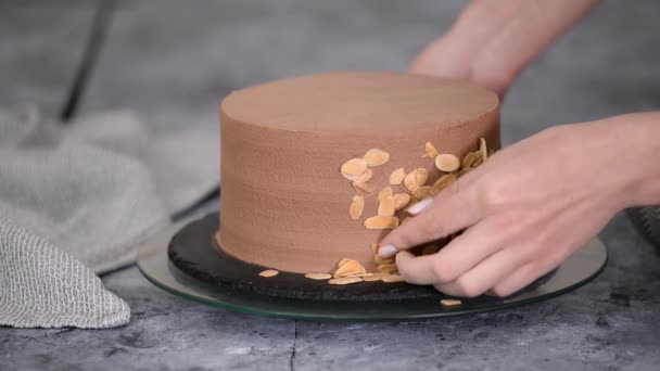 Konditorin bereitet Kuchen zu und dekoriert ihn mit Mandelflocken. — Stockvideo