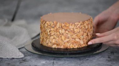Dişi pasta şefi bir pasta hazırlıyor ve onu badem gevreğiyle süslüyor..