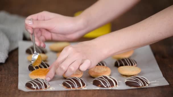 Primer plano de una mano de mujer aplicando mermelada de albaricoque en las galletas. — Vídeos de Stock