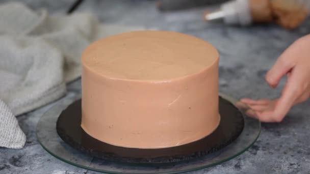 Kadın elleri çikolatalı keki kremayla süslüyor.. — Stok video