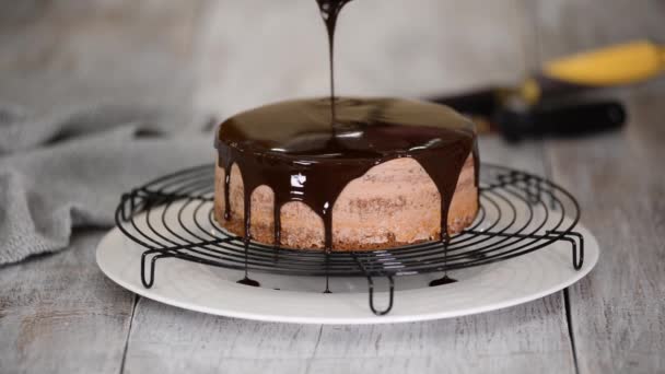 Bolo de chocolate vidrado com chocolate derretido. Mulher derramando chocolate sobre bolo. — Vídeo de Stock