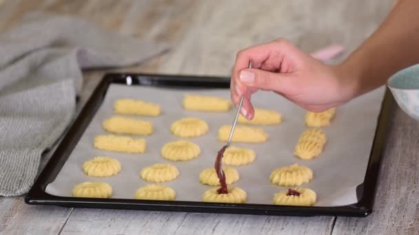 Die Frau reicht ein selbst gebackenes Plätzchen mit Marmelade. Kurabye-Kekse mit Himbeermarmelade. — Stockvideo