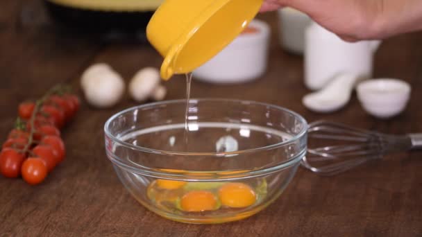 Ανακατεύοντας τρία φρέσκα ωμά αυγά κοτόπουλου σε ένα γυάλινο μπολ. — Αρχείο Βίντεο