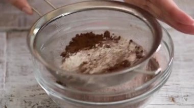 Bir Kız Elleri Kakao Tozu ve unu Masada Kaseye yerleştiriyor.