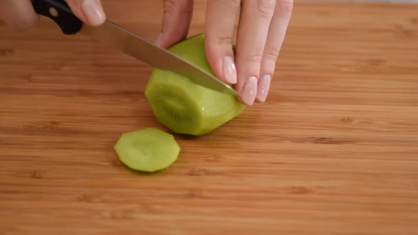 Hände Frauen schneiden frische Kiwi in dünne runde Scheiben. — Stockvideo