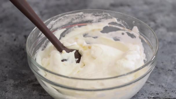 Szpatułka silikonowa w ręce kobiet ostrożnie umieszcza mieszankę posiekanych orzechów nerkowca, cukru i mąki w bitej pianie białek jaj w szklanej misce do pieczenia ciasta kijowskiego. — Wideo stockowe