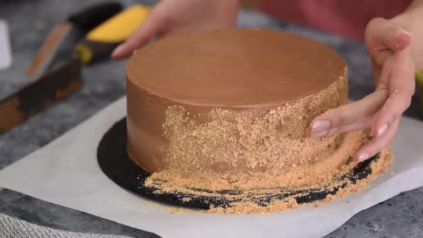 Female hands use the crumbs to decorate the sides of the cake. Making Kiev cake. — Stock Video