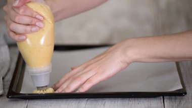 Pasta şefi, şeker poşeti ile tepside taze hamur işi sıkıyor..