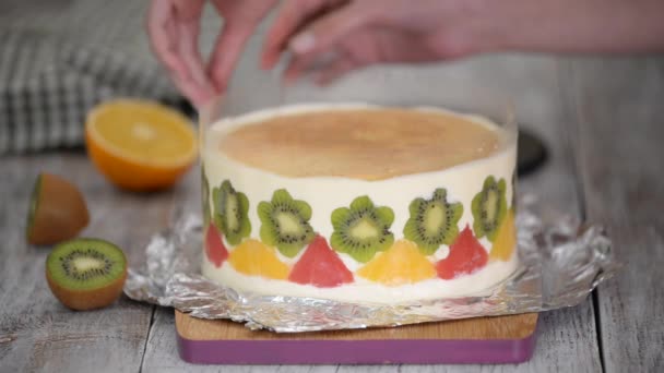 Mujer hace delicioso pastel de mousse de frutas. Pastel decorado con frutas frescas en gelatina. — Vídeos de Stock