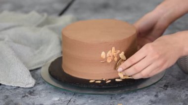 Dişi pasta şefi bir pasta hazırlıyor ve onu badem gevreğiyle süslüyor..