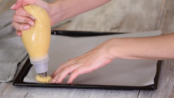 Pečivo Šéfkuchař s cukrářskou taškou mačkající čerstvé těsto na tácu s papírem. — Stock video