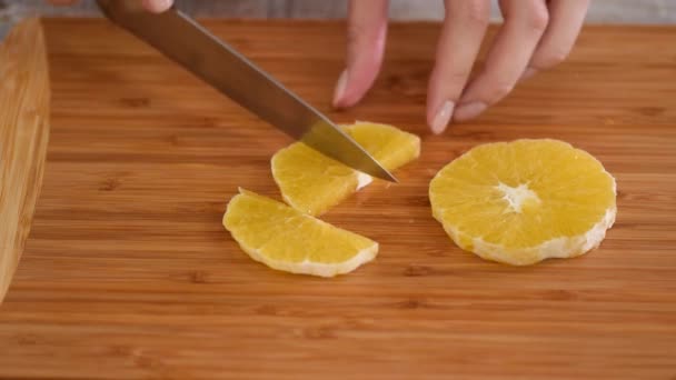 Closeup de frutas de laranja cortadas em tábua de corte de madeira. — Vídeo de Stock