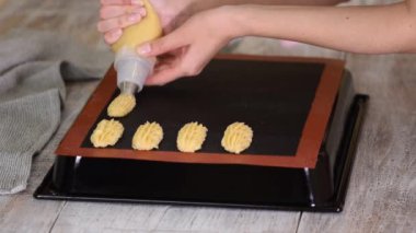 Pasta şefi, şeker poşeti ile tepside taze hamur işi sıkıyor..