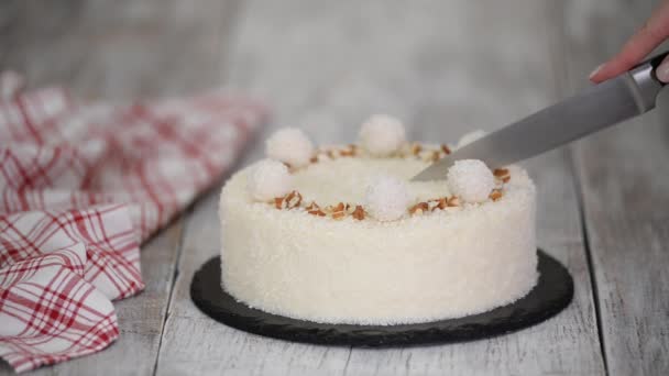 Het snijden van een heerlijke kokosnoot mousse cake, versierd met snoep en amandel. — Stockvideo