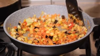 Kızartma tavasında sebze pişiren genç bir kadının yakın çekimi..