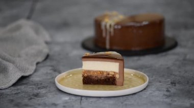 Bir parça çikolatalı, karamelli, fıstıklı, kremalı pasta, tabakta snickers..