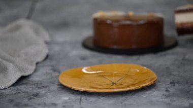 Bir parça çikolatalı, karamelli, fıstıklı, kremalı pasta, tabakta snickers..