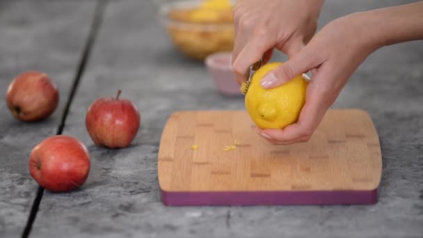 Руки женщины чистят лимонную цедру кожурой. — стоковое видео