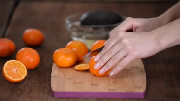 Eine Nahaufnahme weiblicher Hände beim Schneiden einer frischen Mandarine auf einem Schneidebrett. — Stockvideo