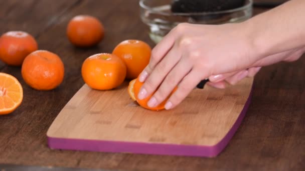 O strânsă de mâini de sex feminin tăind o mandarină proaspătă pe o placă de tăiere . — Videoclip de stoc