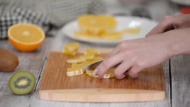 Primer plano de fruta naranja cortada en tabla de cortar de madera. — Vídeos de Stock