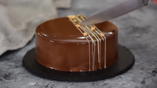 Cutting a chocolate caramel peanut mousse cake and mirror glaze. — Stock Video