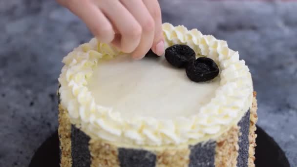 Le mani femminili decorano la parte superiore della torta con prugne secche. — Video Stock