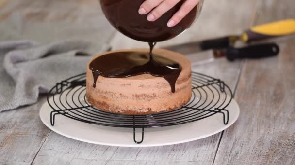 Γλασάρισμα κέικ σοκολάτας με λιωμένη σοκολάτα. Γυναίκα ρίχνει σοκολάτα πάνω από κέικ. — Αρχείο Βίντεο