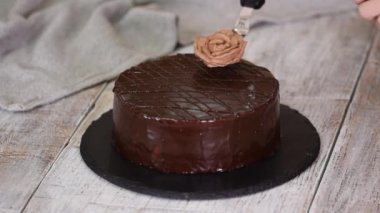 Pasta şefi bir pastayı krema çiçeğiyle süslüyor..