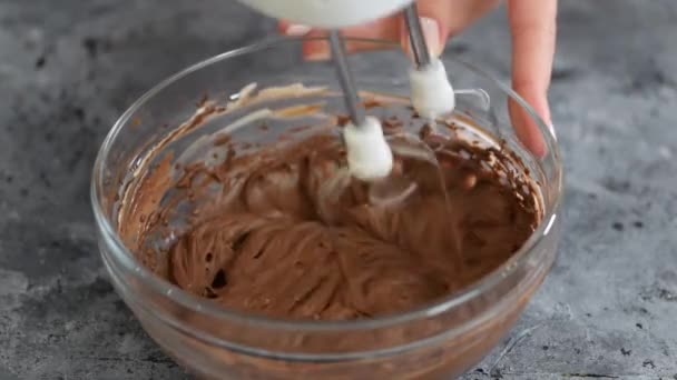 Het mengen van chocolade deeg of beslag voor het bakken van taarten, koekjes, gebak. Menger kloppen chocolade in kom. — Stockvideo