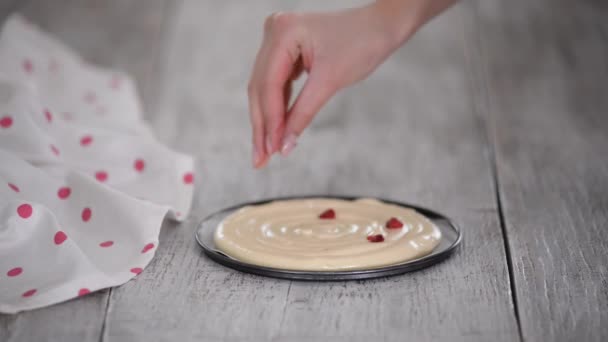 Руки кондитера посыпают замороженную малину на тесто для торта. — стоковое видео