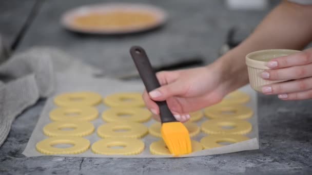 Las manos femeninas engrasan las galletas con clara de huevo en la cocina. — Vídeos de Stock