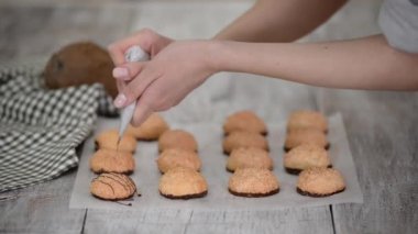 Çikolata sosu parşömen kağıdına hindistancevizli badem kurabiyesi dökülüyor..