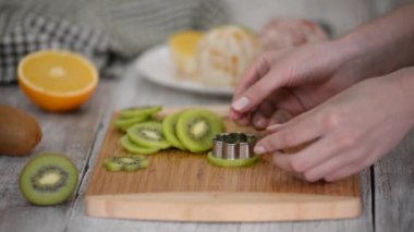 Kadın eli, bir kivinin çiçeğini kurabiye bıçağıyla kesiyor..