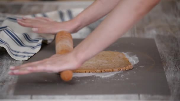 Händerna rulla ut degen med en rullande stift på ett bord, i köket närbild. — Stockvideo