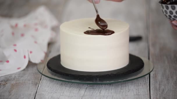 Primo piano di uno chef di pasticceria che versa cioccolato liquido su una torta alla panna bianca. — Video Stock